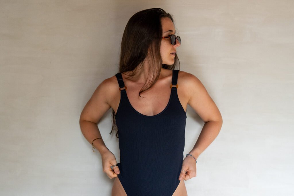 Femme en maillot de bain une pièce noir - les lignes épurées, le dos ouvert et les jambes échancrées définissent la tendance moderne des maillots une pièce pour 2025.